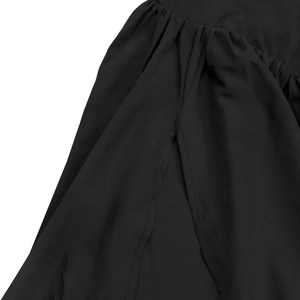 Detail shot of black dress showing high slit design and pleated fabric texture