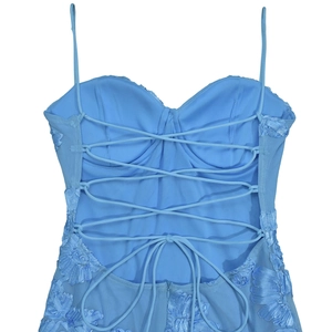 Dettaglio dell'abito a corsetto azzurro con ricami floreali e lacci sulla schiena nuda