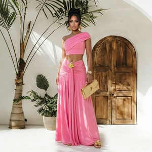 Détail d'un ensemble deux pièces rose avec drapé à la taille et fleur dorée sur la jupe
