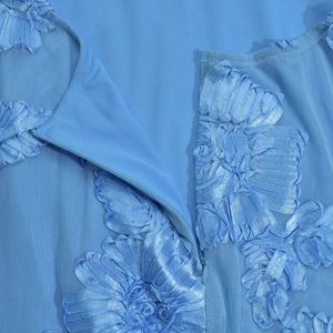 Dettaglio del vestito celeste in mesh con fiori 3D in nastro e cerniera invisibile
