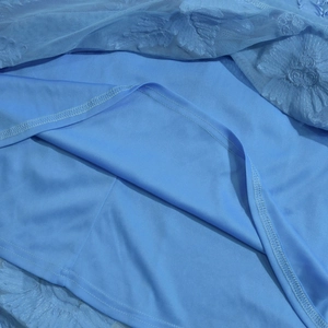 Dettaglio dell'abito azzurro che mostra il pizzo floreale e le cuciture della fodera