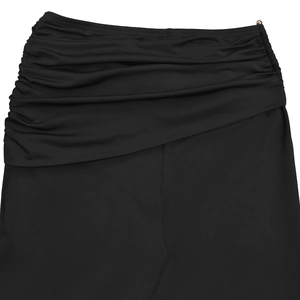 Close-up detail of black ruched skirt featuring asymmetrical draped fabric and a metal buckle