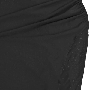 Detailed view of elegant black dress featuring sheer polka dot mesh and gathered fabric