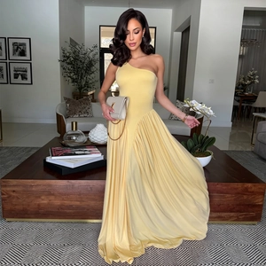 Detail of elegant one-shoulder evening dress with asymmetric pleated yellow flowing skirt