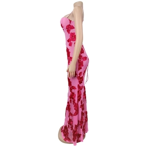 Dettaglio del vestito lungo rosa con applicazioni floreali in pizzo rosso e spalline