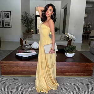 Detail view of yellow one-shoulder satin evening gown with pleated waist and flowing hem