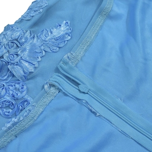 Détail macro de la broderie florale 3D bleu clair et zip invisible sur la robe