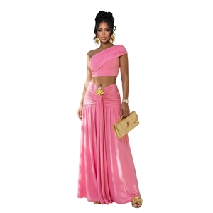 Détail du haut court rose à une épaule et jupe maxi froncée avec boucle fleurie dorée