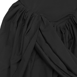 Detailed close-up of gathered side seam on elegant black mini dress with pleated texture