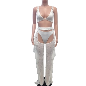 Detail of white mesh trousers featuring faux pearl beads and ruffled side accents