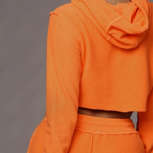 Dettaglio del set felpa con cappuccio corta arancione e pantaloni a vita alta