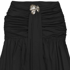 Détail du tissu noir froncé avec une boucle métallique florale dorée au centre