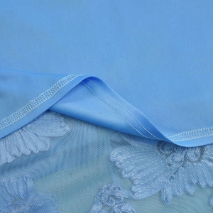 Detailed close-up of light blue mesh lace hem and knit fabric stitching on dress