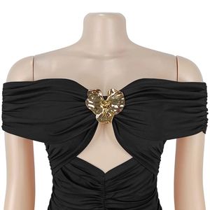 Détail de robe noire à épaules dénudées avec un grand accessoire floral en métal doré