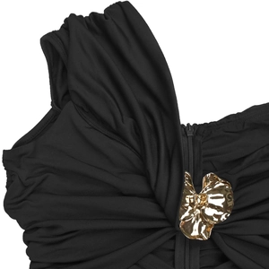 Détail d'une robe froncée noire avec fleur métallique dorée 3D et fermeture éclair