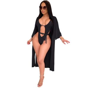 Détail d'un maillot de bain noir à découpes avec cache-maillot à manches longues sur blanc
