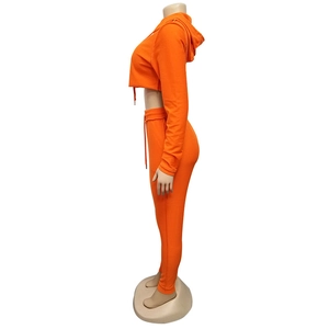 Vista laterale di felpa corta con cappuccio arancione e leggings coordinati da donna