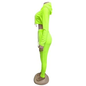 Vista laterale del set due pezzi verde neon con felpa corta con cappuccio e joggers aderenti