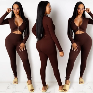 Drie weergaven van een donkerbruine ribgebreide set met rits-crop top en een strakke legging
