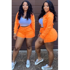 Detail of orange velvet loungewear set featuring a zip-up hoodie and drawstring shorts
