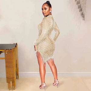 Detail of champagne bodycon dress with intricate white pearls and tassel hemline
