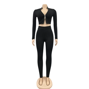 Detail van een zwarte ribgebreide tweedelige set met korte rits-top en hoge taille legging