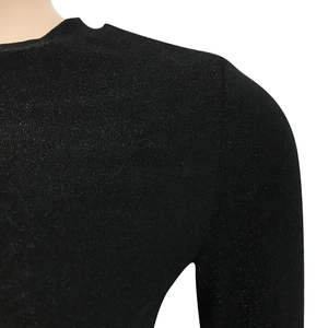 Dettaglio dell'abito in maglia nera con riflessi discreti e trama del girocollo