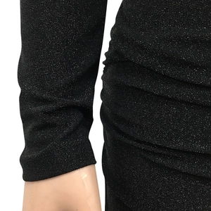 Dettaglio del tessuto glitterato nero con trama a pieghe e polsini elastici su abito lungo