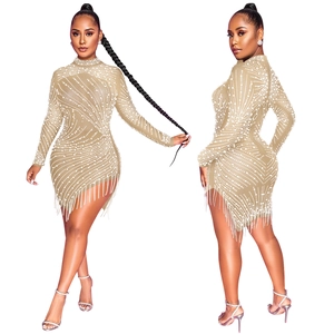 Detailed view of nude bodycon dress featuring white pearls and flowing fringe tassels
