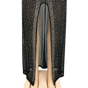 Détail d'une robe en résille noire transparente ornée de strass argentés et fente haute