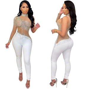 Detail of sheer mesh bodysuit with rhinestones and white slim fit trousers