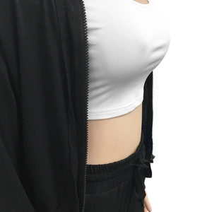 Detail of a black zip-up hoodie layered over a white fitted crop top and drawstring pants