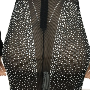 Détail des strass argentés scintillants sur une robe de soirée en maille noire transparente