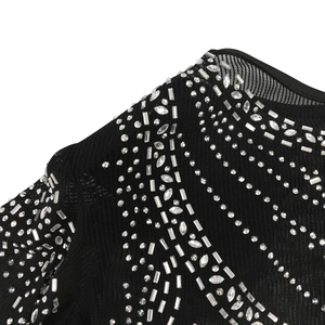 Détails du décolleté en résille noire orné de strass argentés scintillants sur la robe