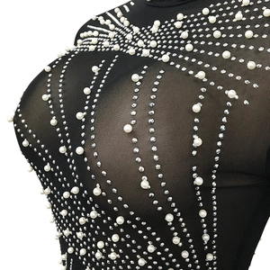 Detailed close-up of sheer mesh fabric with hand-applied pearls and crystal rhinestones