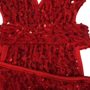 Close-up of red sequined velvet fabric with V-neck design and wide waist belt detail