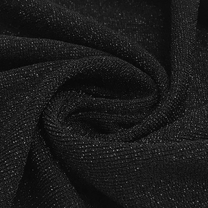 Vista macro del tessuto nero glitterato che mostra la trama luccicante e le pieghe