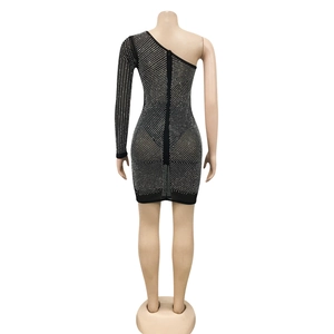 Détail des strass argentés sur le tissu en maille noire de la robe asymétrique