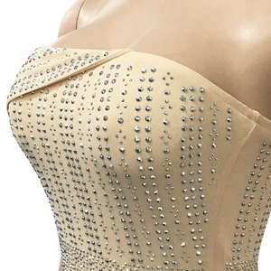Close-up of sparkling silver rhinestones on beige mesh fabric for evening dress