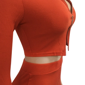 Detailopname van feloranje geribbelde gebreide crop top met een metalen ritssluiting