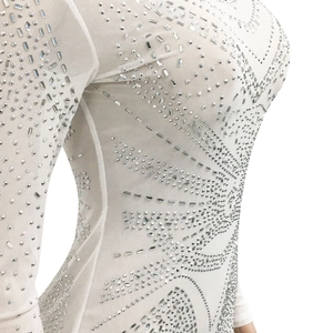 Détail d'une robe en résille blanche avec des motifs complexes en strass argentés