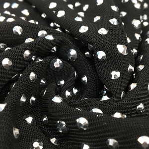 Dettaglio macro del tessuto a rete nero con strass argentati lucidi su un abito lungo