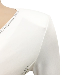 Detailed view of deep V-neckline and silver rhinestone patterns on white dress