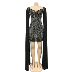 Detail of black evening dress featuring wavy rhinestone patterns and long cape sleeves