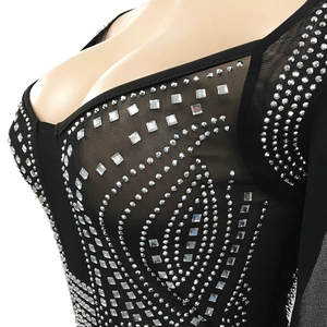 Detail of sheer black mesh dress with intricate silver rhinestones and deep V-neckline