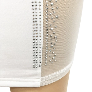 Close-up of white dress with sheer mesh panel and vertical rows of sparkling rhinestones