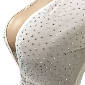 Dettaglio dell'abito in rete bianca con strass argentati brillanti e trama elegante