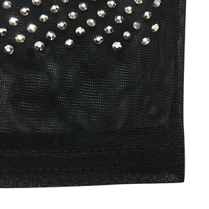 Détail du tissu en maille noire avec des strass argentés brillants et des bordures bien finies
