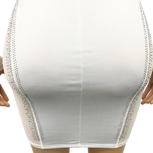 Close-up of white bodycon mini dress featuring sparkling silver rhinestone side detailing