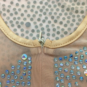 Detail of sheer mesh jumpsuit featuring shimmering rhinestones and invisible zipper closure